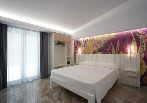 Harmony Tropea Rooms & Suites في تروبيا: غرفة نوم بسرير ابيض كبير وجدارية