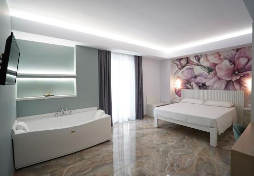 Harmony Tropea Rooms & Suites في تروبيا: غرفة نوم بيضاء مع سرير وحوض استحمام