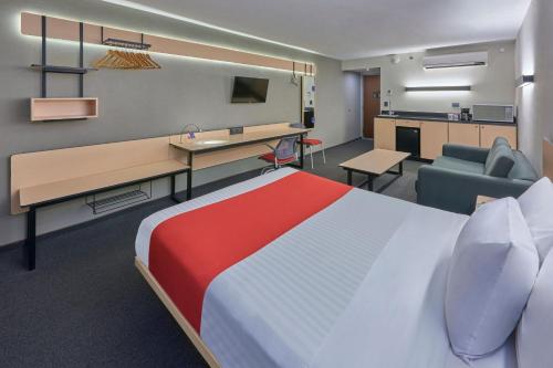 Cette chambre comprend un lit, un bureau et un canapé. dans l'établissement City Express by Marriott Cananea, à Cananea