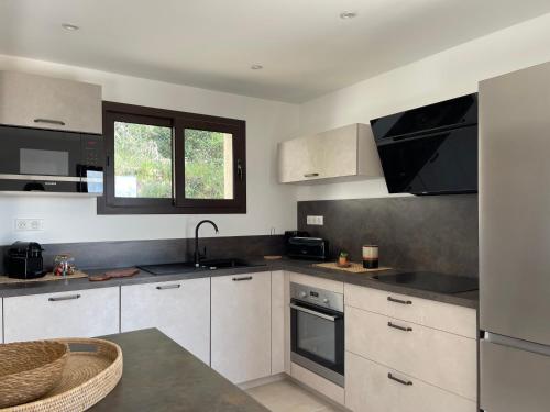 une cuisine avec des armoires blanches et des comptoirs noirs dans l'établissement Les Hauts de Capo - Domaine privé à proximité de Porto-Vecchio, à Lecci