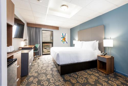 a hotel room with a large bed and a kitchen at Regency Miami Airport by Sonesta in Miami