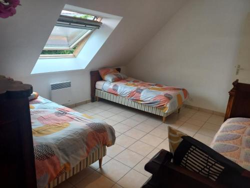 une chambre mansardée avec deux lits et une fenêtre dans l'établissement Binic 700m de la plage 4 chambres, jardin, linge, wifi, à Binic