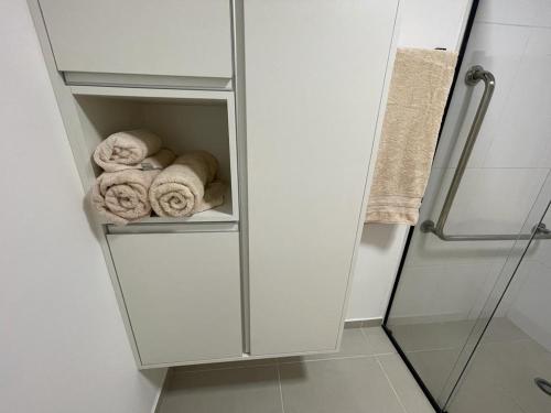 - une armoire blanche avec des serviettes laminées dans la salle de bains dans l'établissement FLAT Paulista com varanda perto do Metrô, à São Paulo