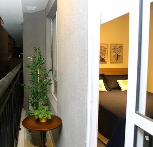 Cette chambre comprend un lit et une table avec une plante. dans l'établissement FLAT Paulista com varanda perto do Metrô, à São Paulo