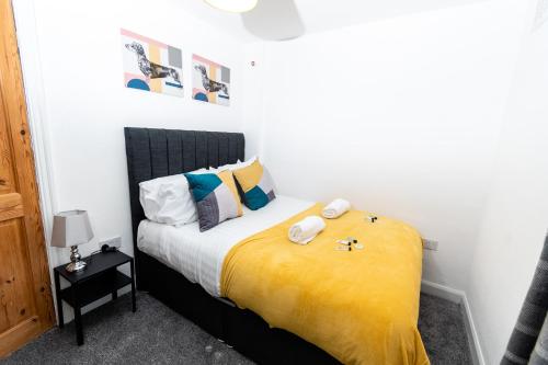 a bedroom with a bed with yellow sheets and pillows at Greenbourne - 4 bedrooms Sleeps 8 free parking in Gateshead