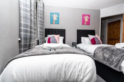 a bedroom with two beds with white and pink pillows at Greenbourne - 4 bedrooms Sleeps 8 free parking in Gateshead