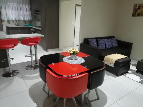 a living room with a red table and red chairs at Beautiful & Serene Airbnb house in Klerksdorp