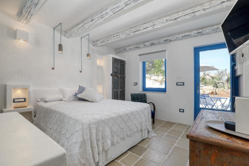 a white bedroom with a bed and a window at Trulli Terra Magica in Putignano