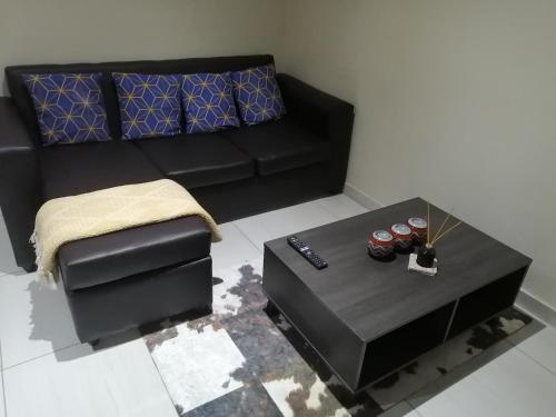 a living room with a black couch and a table at Beautiful & Serene Airbnb house in Klerksdorp