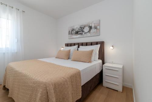 a white bedroom with a large bed with white sheets and pillows at Apartment New Bridge Trogir in Trogir