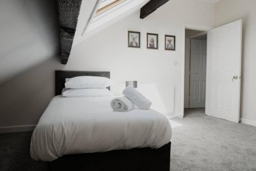 a bedroom with a bed with white sheets and pillows at Bentley Lofts - By Sigma Stays in Crewe