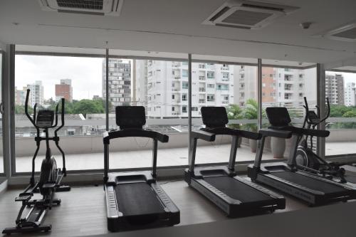 Apartaestudio DISTRITO 90 في بارانكويلا: صالة ألعاب رياضية مع أربعة أجهزةٍ جري أمام نافذةٍ كبيرة