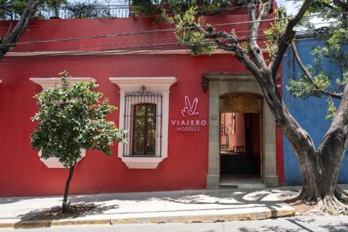 a red building with a tree in front of it at Viajero Oaxaca Hostel in Oaxaca City