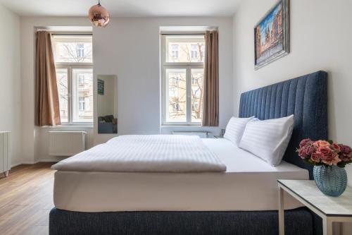 a bedroom with a large bed and two windows at Prague Tales Boutique Residence by Dwellfort in Prague