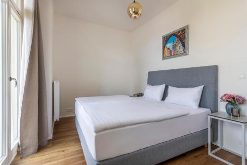 1 dormitorio con 1 cama con sábanas blancas y ventana en Prague Tales Boutique Residence, en Praga