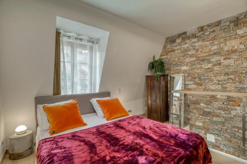 um quarto com uma cama e uma parede de tijolos em Le Baroque clim et sauna em Annecy