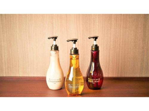 three bottles are sitting on a wooden shelf at Y's Inn Naha Oroku Ekimae - Vacation STAY 25852v in Naha