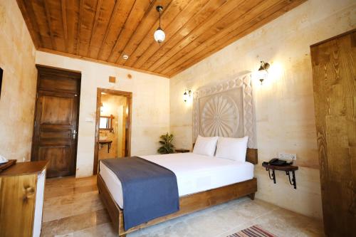 a bedroom with a bed and a wooden ceiling at Rocca Stone House in Goreme