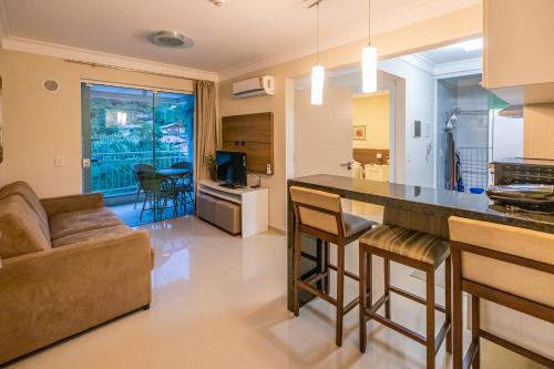 a kitchen and living room with a couch and a table at Flat com Piscina Térmica no Bombinhas Summer Beach in Bombinhas