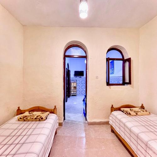 two beds in a room with two arched windows at Oldtown House in Chefchaouene