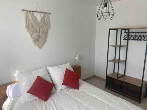 sypialnia z białym łóżkiem z czerwonymi poduszkami w obiekcie Le Val des Prats proche de Rocamadour w mieście Puybrun