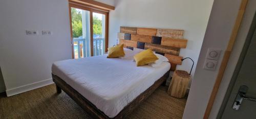 a bedroom with a bed with white sheets and yellow pillows at Jack's Lodge - La Grange in Tosse