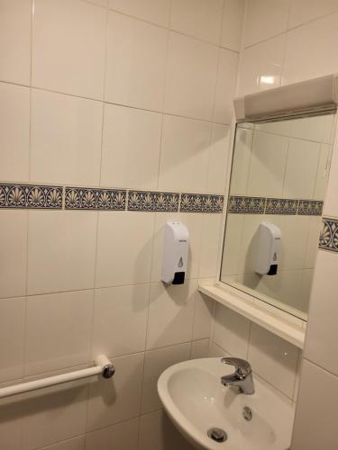 a white bathroom with a sink and a mirror at All Seasons Gatwick Guest House & Parking in Horley