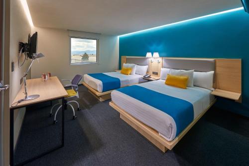 a hotel room with two beds and a desk at City Express by Marriott Suites Toluca in Toluca