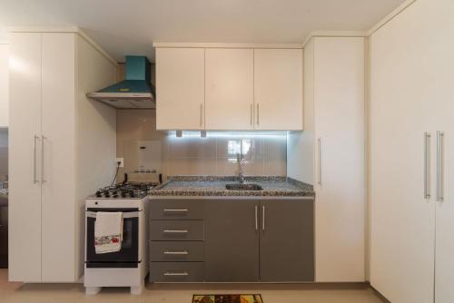 uma cozinha com armários brancos e um forno com placa de fogão em Apto com varanda gourmet em Canela CBL307 em Canela