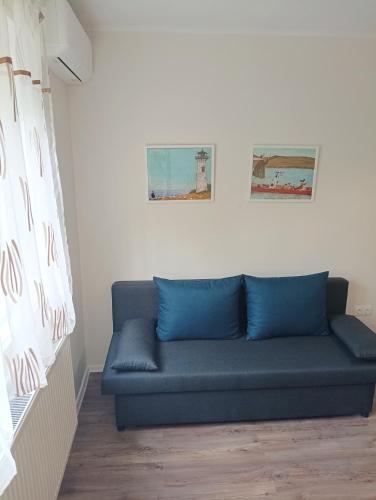 ein blaues Sofa in einem Zimmer mit zwei Bildern an der Wand in der Unterkunft SaraHome3 Center in Szeged