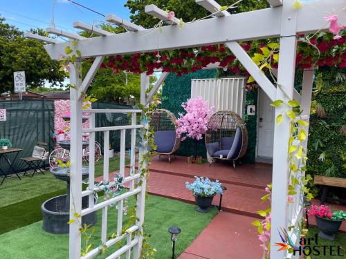 eine weiße Pergola mit Stühlen und Blumen in der Unterkunft Art Gardens Wynwood concept in Miami
