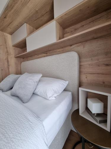 um quarto com uma cama branca e uma parede de madeira em Citylux Grand Apartment em Zagreb