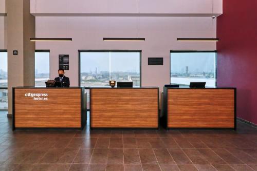 a man sitting at a desk in an airport lobby at City Express by Marriott Monterrey Universidad in Monterrey