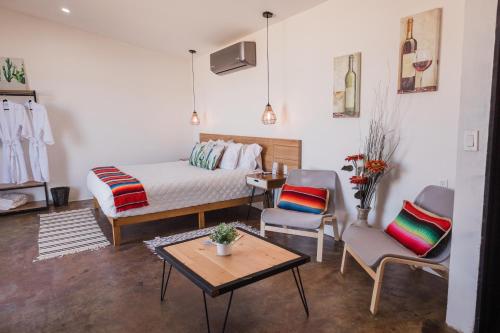 een kamer met een bed en twee stoelen en een tafel bij Villa Loar, Valle de Guadalupe in El Porvenir