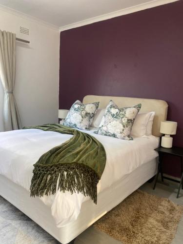 ウムタタにあるUrban & Comfortable Loft apartment in Mthathaの紫の壁の白いベッドが備わるベッドルーム1室