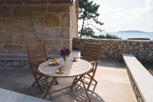 a wooden table and two chairs on a patio at Aldea Soma in Carnota