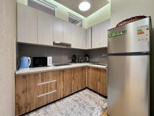 a stainless steel refrigerator in a kitchen with wooden cabinets at Dushanbe City View Apartment in Dushanbe