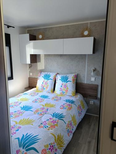 a bedroom with a bed with a colorful comforter at mobil-home neuf 4-6 places camping Siblu les viviers in Lège-Cap-Ferret