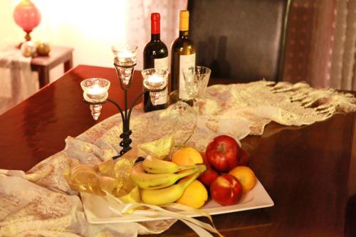 un piatto di frutta su un tavolo con bottiglie di vino e bicchieri di Edem House a Volos
