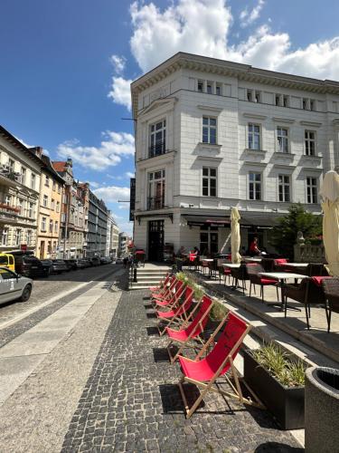 uma fila de cadeiras e mesas numa rua com um edifício em Apartament MARILYN w Kamienicy Wicherkiewiczów em Poznań