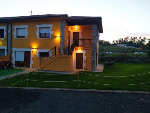 a yellow house with a staircase in a yard at APARTAMENTOS EL ROJU in Santillana del Mar