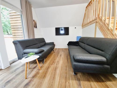 sala de estar con sofá negro y mesa en Ferienhaus88 am Twistesee, en Bad Arolsen
