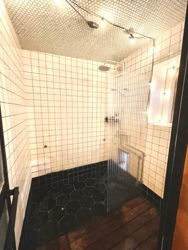 a bathroom with a shower with black and white tiles at 三丁庵ゲストハウス 水質AAビーチまで徒歩15分ペリーロードまで徒歩5分最高なロケーション 下田を遊び尽くせるゲストハウス 無料駐車場もありますJapanese old style guest house that 2 minutes walk to Perry Road 15ninutes walk to Nabeta beach in Harada