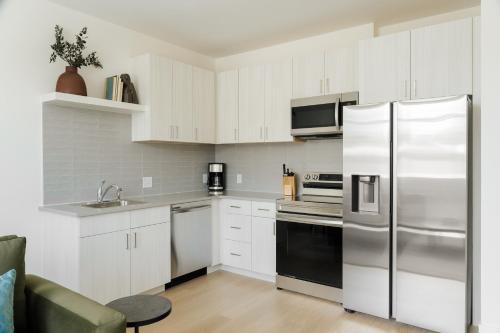 a kitchen with white cabinets and a stainless steel refrigerator at Sonder Ceros in Denver