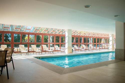 a swimming pool with chairs and tables and a building at Flat 333 - Luxo e Vista da Pedra Azul in Pedra Azul