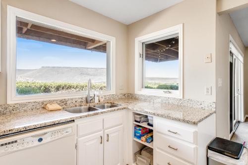a kitchen with white cabinets and a sink and two windows at Southern Utah Realness in St. George