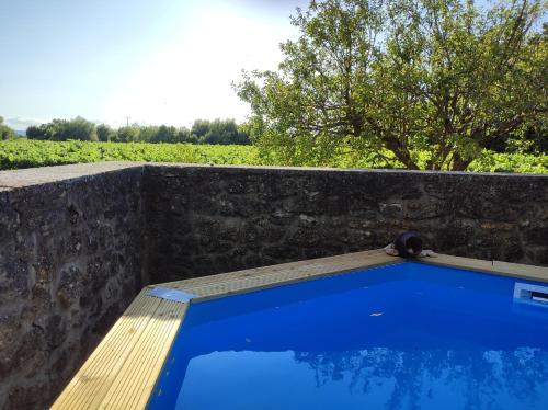 una piscina azul con una pared de piedra y un banco de madera en Mas du Vieux Moulin, en Sérignan-du-Comtat