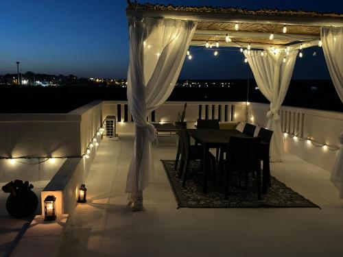 een patio met een tafel en witte gordijnen en verlichting bij Casa alle Colonne in Maruggio