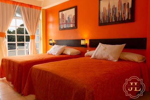 Hotel JL في Tierra Blanca: سريرين في غرفة بجدران برتقالية