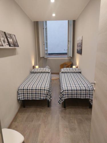 two beds in a small room with a window at Appartamento Piazzetta La Maddalena in Savona